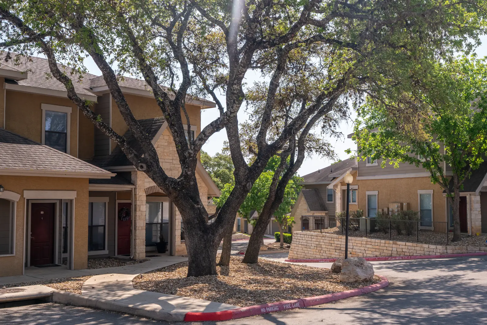 Mature oak canopy, river rock beds and curved walkways at Providence Estates Townhomes